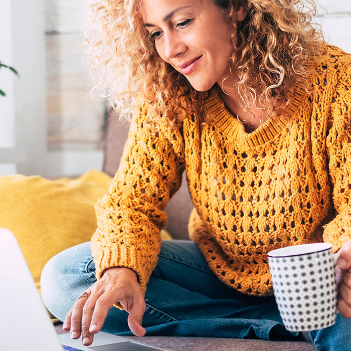 Woman sitting on couch while working on laptop