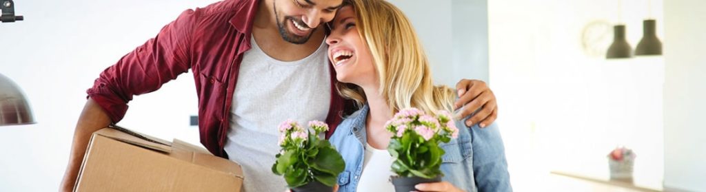 Couple laughing together while moving into house