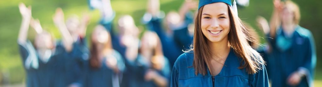 Graduate posing for photo with other graduates in the background