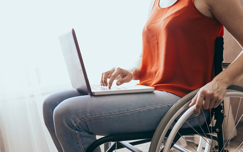 Woman sitting in wheelchair while working on laptop