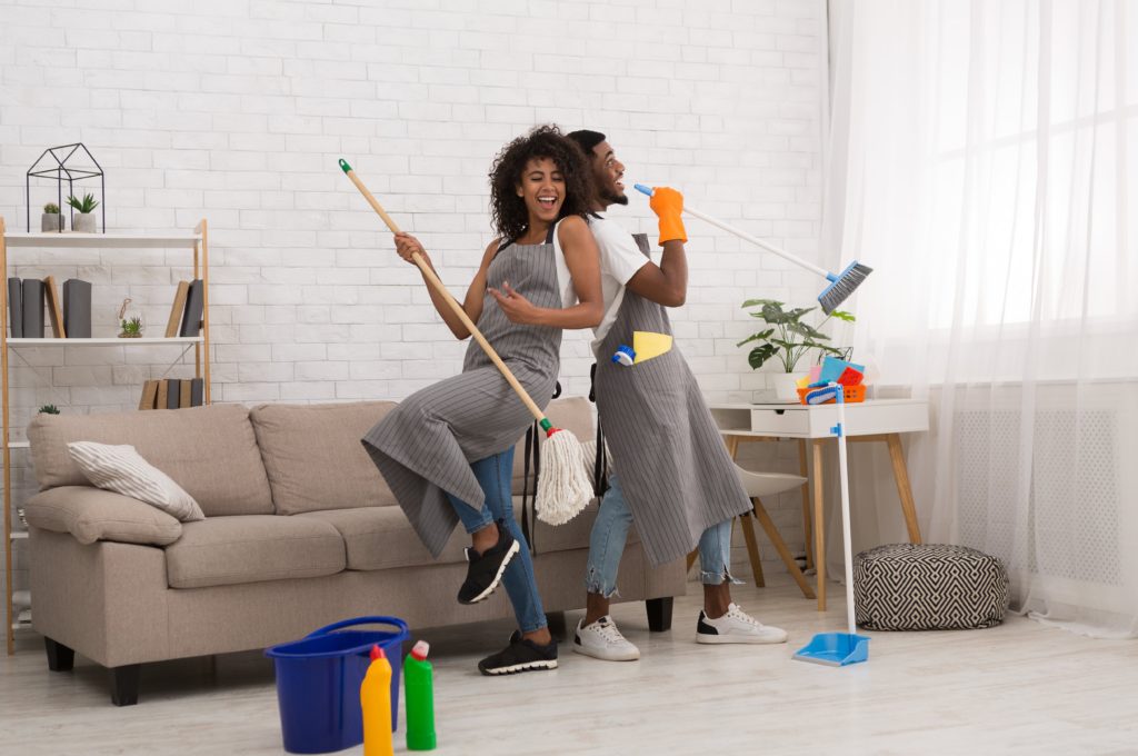 Couple pretending to be in a band while cleaning together inside home
