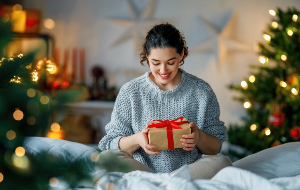 Lady opening gift in front of Christmas tree