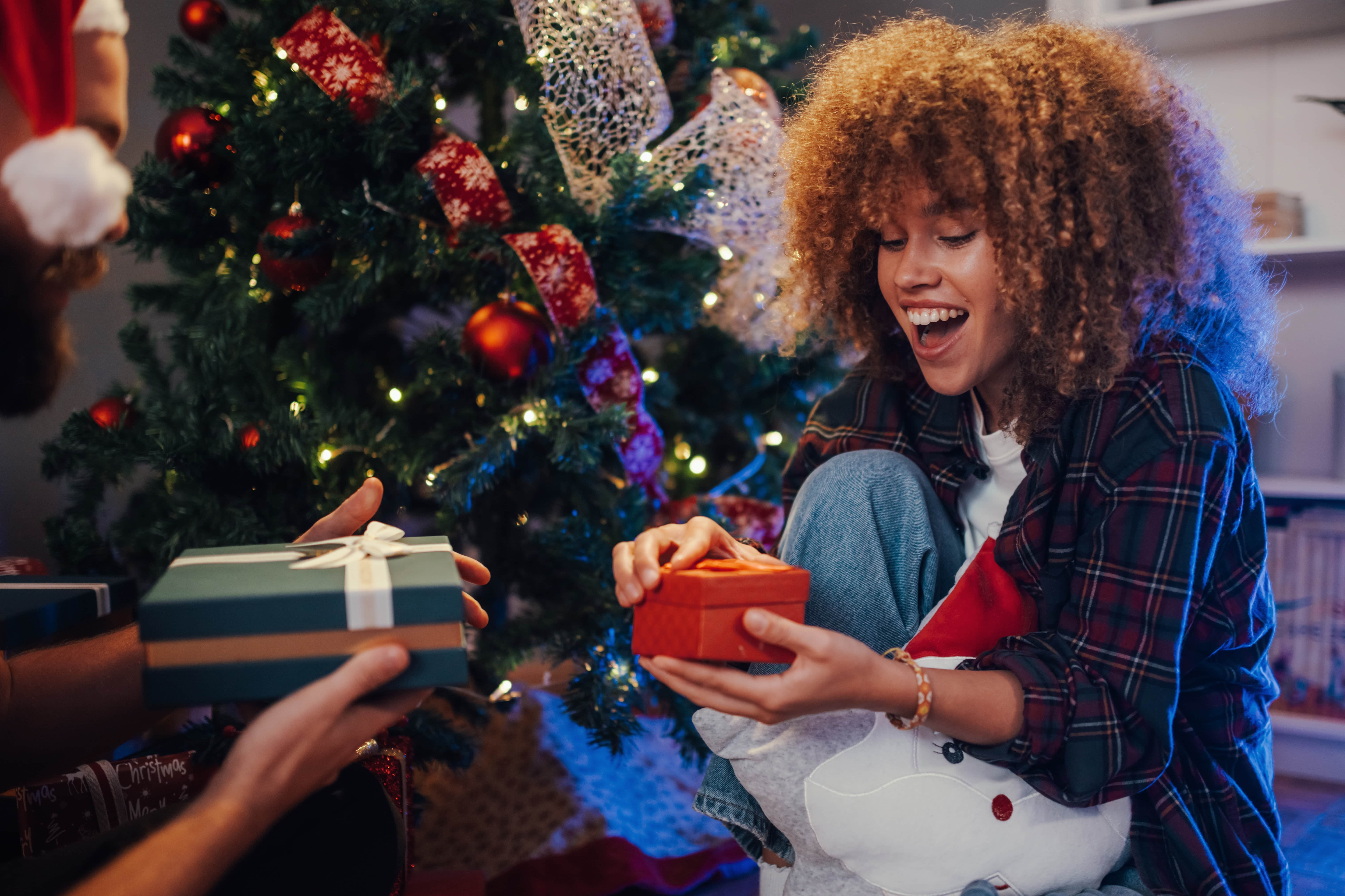 Lady opening gifts in front of Christmas tree